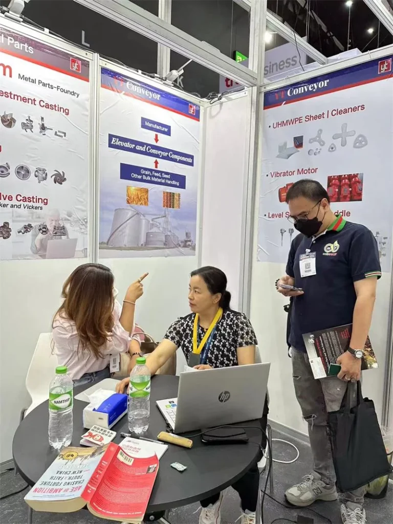 Grupo de clientes consultando productos industriales y sistemas conveyor en el stand de YT Conveyor